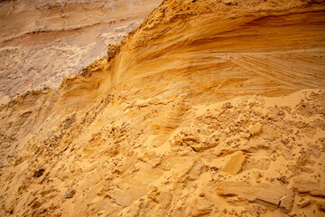 Textural sand, with  relief surface, multi-colored layers and different in size of granules, in outdoor sand career, after mining ore and sand for construction.