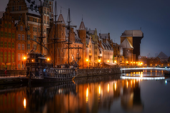 Beautiful architecture of the old town in Gdansk by the Motława river with a historic port crane at wintery night. Poland