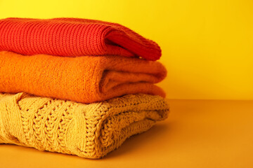 Stack of autumn clothes on color background, closeup