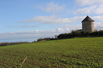 Obraz na płótnie Canvas A tower on farmland with green meadow and blue sky in Brittany, France