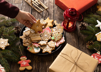 Plate full of homemade cookies and biscuits shaped in winter holiday traditional Christmas and New Year themes and motives placed on a wooden table