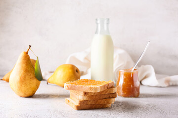 Bread with tasty pear jam and bottle of milk on table