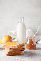 Bread with tasty pear jam and bottle of milk on table