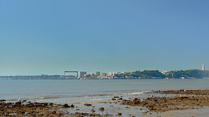Very low tide on the Tagus river, showing the rocks of the river floor, with Almada harbor in Lisbon