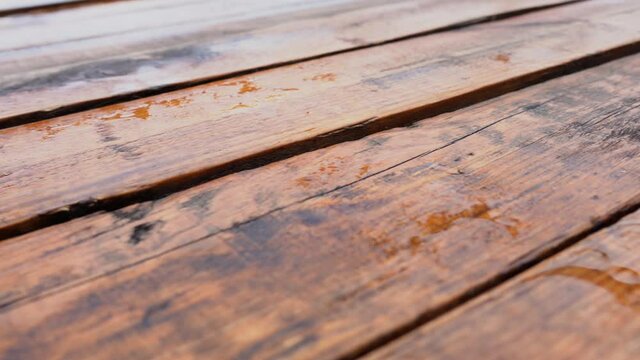Wet brown wooden planks of wooden brown terrace. Surface of organic wood floor with many rainy puddles after heavy rain or thunderstorm. Abstract low angle view 4k stock video background