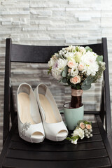 Wedding accessories: Bride's shoes, rings, boutonniere, and elegant wedding bouquet with tea roses, white dahlias and brunei 