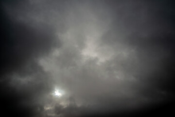 Dark cloudy sky through which the sun shines