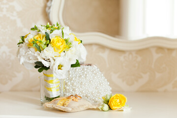 Tender Bride's bouquet in yellow and white colors and wedding rings on a pillow