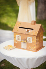 Wedding ceremony decoration in the garden. A box for money and card gifts in a view of house