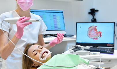 Woman having her teeth 3d scanned by professional dentist.