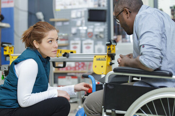 saleswoman helping a man in wheelchair