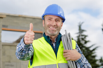 tradesman with reel of cable on shoulder giving thumbs up