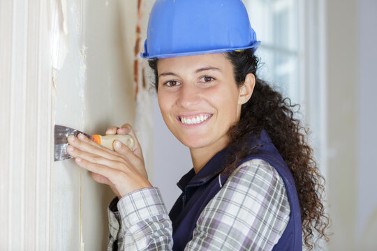 happy woman repairs wall with spackling paste