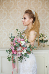 Pretty young Bride. Blonde-haired woman with wedding hair-style with a long tail. Boudoir morning of the bride. Looking to the camera or on her wedding bouquet