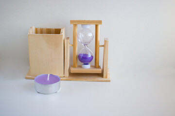 On a white background, a transparent hourglass with flowing lilac sand. The old classic timer. The concept of time, new year. Place for your text