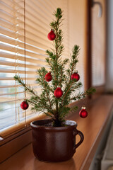 Small decorated alternative Christmas tree in a pot on a windowsill