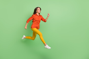 Fototapeta na wymiar Photo of excited sweet mature lady dressed red shirt jumping high running fast empty space smiling isolated green color background