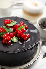 Tasty homemade chocolate cake with berries and mint on white table, closeup