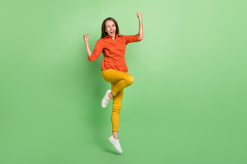 Fototapeta na wymiar Full body photo of pretty young lady celebrate victory fists hands jumper isolated over green color background