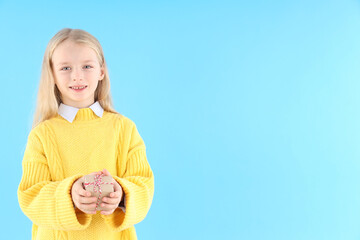 Cute little girl holds gift box on blue background
