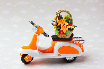 A toy scooter delivering a basket of flowers.  The concept of fast flower and gift delivery