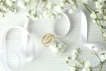 Concept of wedding accessories with wedding rings on white wooden background