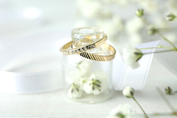 Concept of wedding accessories with wedding rings on white wooden background