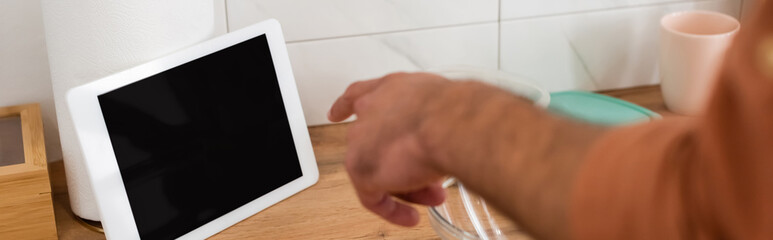 Cropped view of man pointing at digital tablet in kitchen, banner