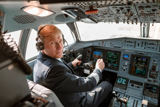 Male pilot in headphones sitting in airplane cockpit