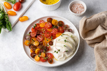 Ball of mozzarella cheese with sliced tomatoes, caprese salad.