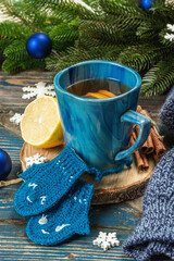 Hot drink with crocheted funny mittens. Traditional winter decor, fir tree branches, snowflakes