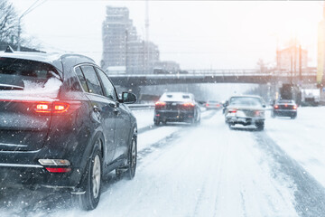 Scenic view snow covered city highway slippery road drive cars moving fast speed motion. Snowfall danger blizzard bad winter weather conditions. Urban cold snowy day snowstrom town background