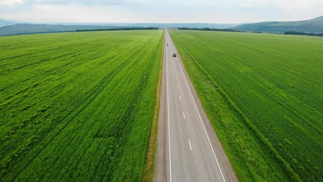 4k aerial view. Drone is following to a car which is rides on the road among agricultural fields. Adventuring on the car. Top view onto moving car. The concept of travel.