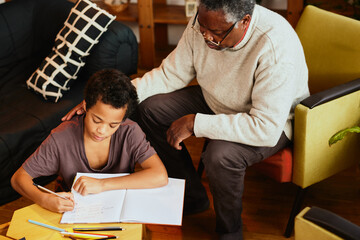 An African grandfather showing to his grandson how to solve a math problem. Family support