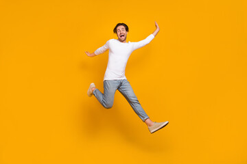 Fototapeta na wymiar Full body photo of scared brunet young guy run wear shirt jeans sneakers isolated on yellow background