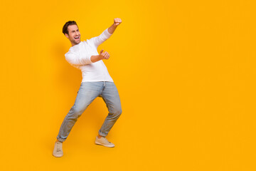 Fototapeta na wymiar Full length photo of impressed brunet millennial guy drive wear shirt jeans footwear isolated on yellow background