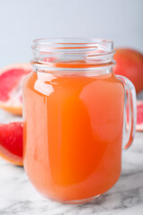 Tasty freshly made grapefruit juice on white marble table