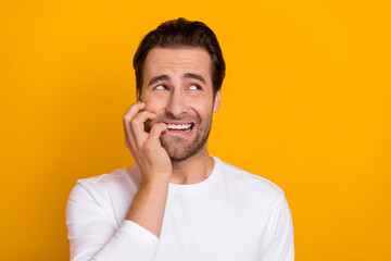 Photo of young stressed brunet guy look empty space wear white shirt isolated on bright yellow color background