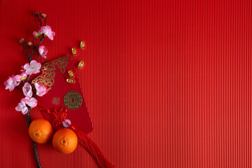 Chinese new year festival decorations. Orange, leaf, red packet, plum blossom on red background. - Powered by Adobe