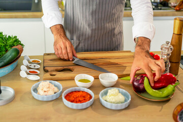 The cook is cutting the onion on a wooden board