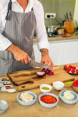 The cook is cutting the onion on a wooden board