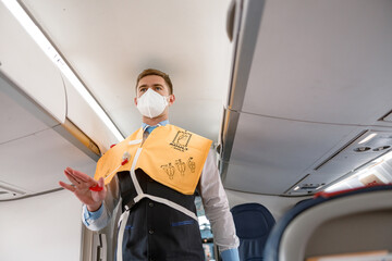 Flight attendant demonstrating how to use life vest in aircraft