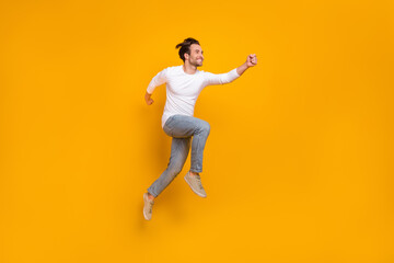 Obraz na płótnie Canvas Full length photo of cute brunet millennial guy run wear shirt jeans shoes isolated on yellow background