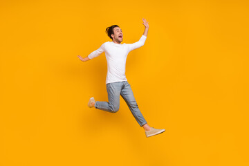 Full length photo of stressed brunet millennial guy run wear shirt jeans shoes isolated on yellow background