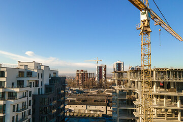 Aerial view of high tower crane and residential apartment buildings under construction. Real estate development