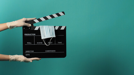 Face mask on Clapper board or movie Clapperboard and hand wear white medical gloves on green mint...