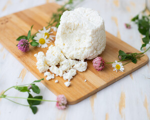 Ricotta cheese lies on a wooden board with wildflowers.