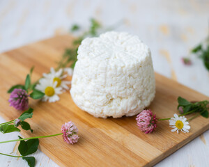 Ricotta cheese lies on a wooden board with wildflowers.