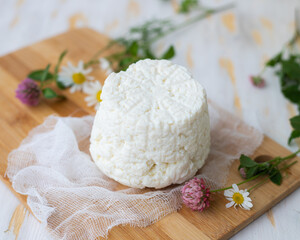 Ricotta cheese lies on a wooden board with wildflowers.