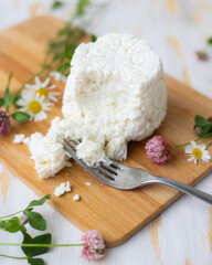 Ricotta cheese lies on a wooden board with wildflowers.